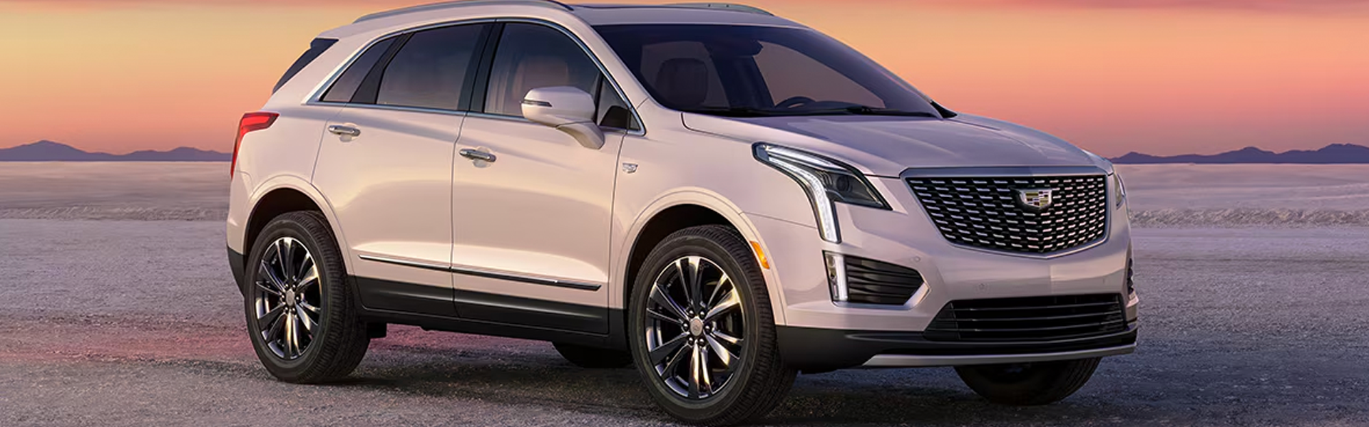 White Cadillac XT5 parked at sunset.
