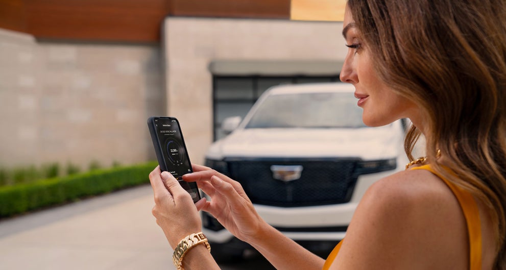 lady checking her mobile with a Cadillac vehicle background | Cincinnati Cadillac in Cincinnati OH